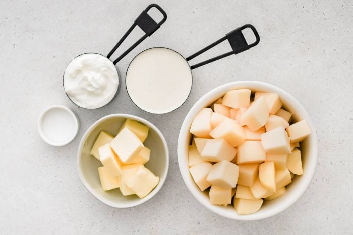 All of the ingredients needed to make crockpot mashed potatoes in individual measuring cups and ramekins.