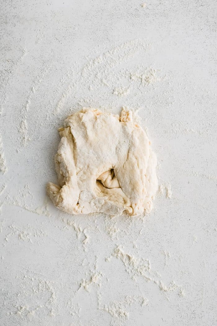 Gathered scraps of buttermilk biscuit dough on a floured work surface.