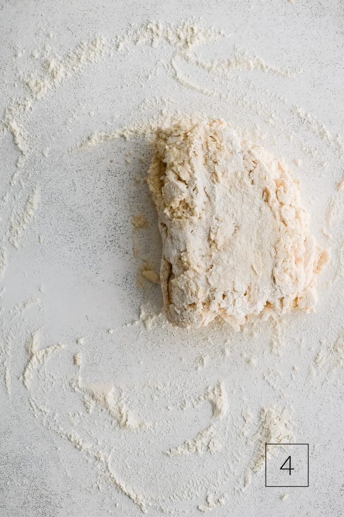 Buttermilk biscuit dough roughly shaped into a rectangle and folded in half on a lightly floured work surface.