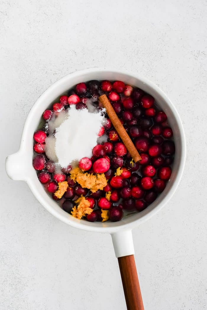 All of the ingredients needed to make cranberry sauce in a medium sauce pot.