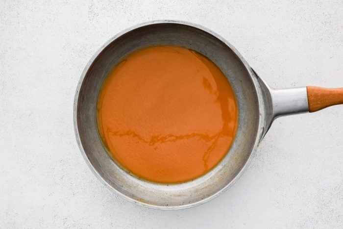 A dark brown roux in a large stainless steel skillet.