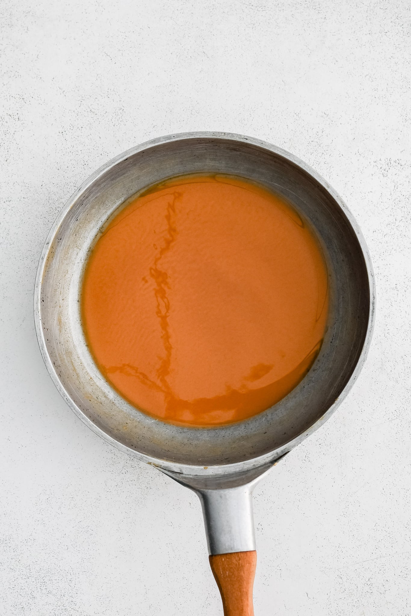 A dark brown roux in a large stainless steel skillet.