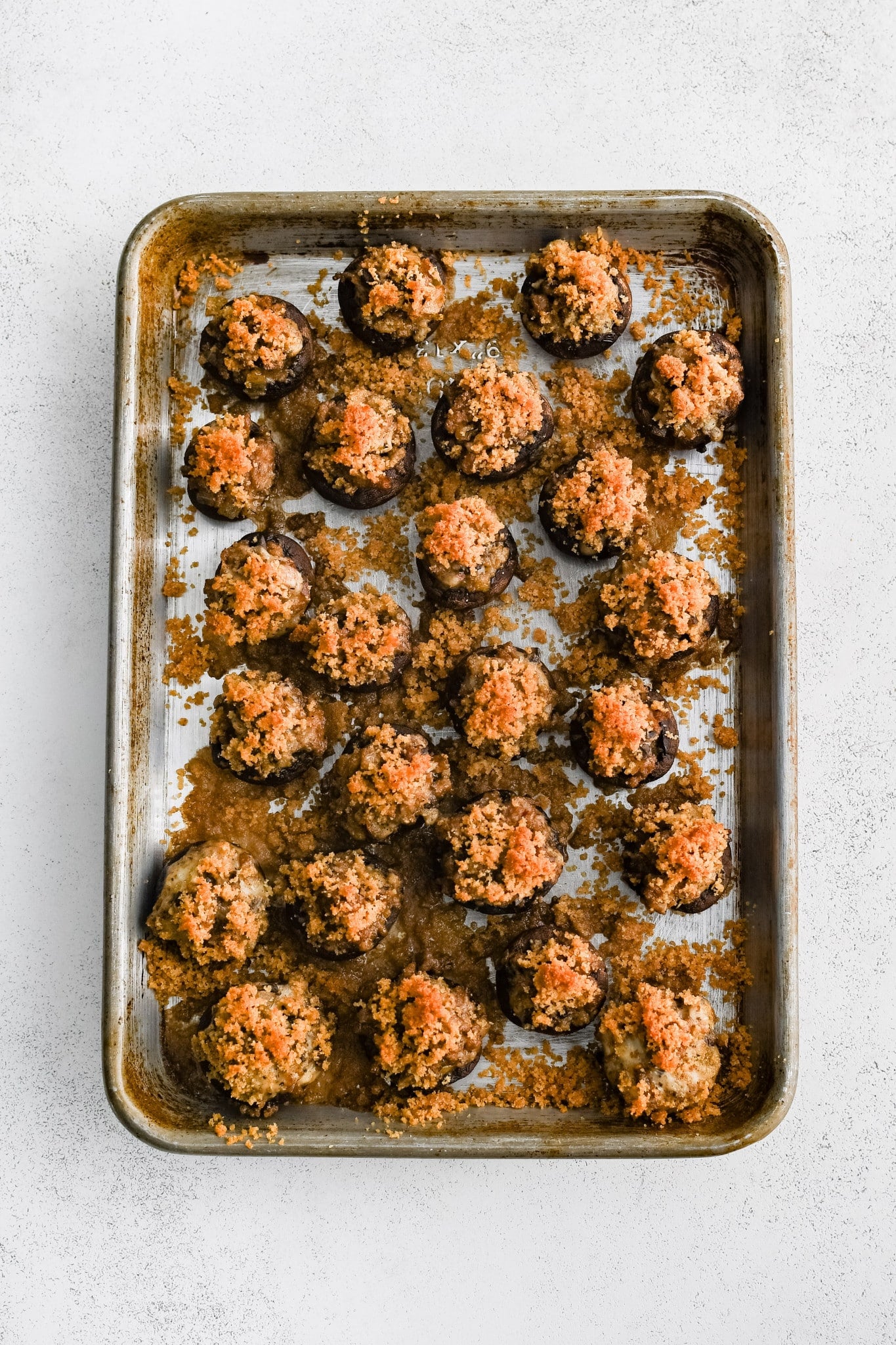 Baked sausage stuffed mushrooms on a large baking sheet with golden crispy breadcrumb tops.