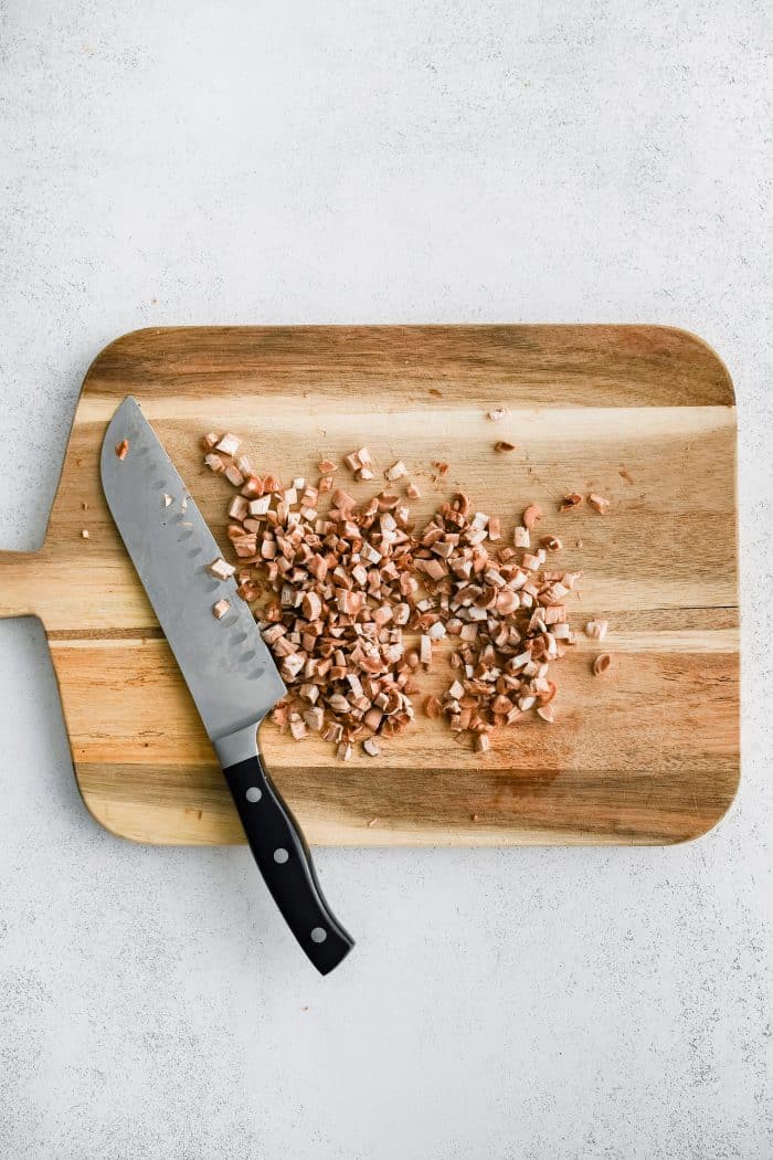 Large cutting board with finely chopped mushroom stems.