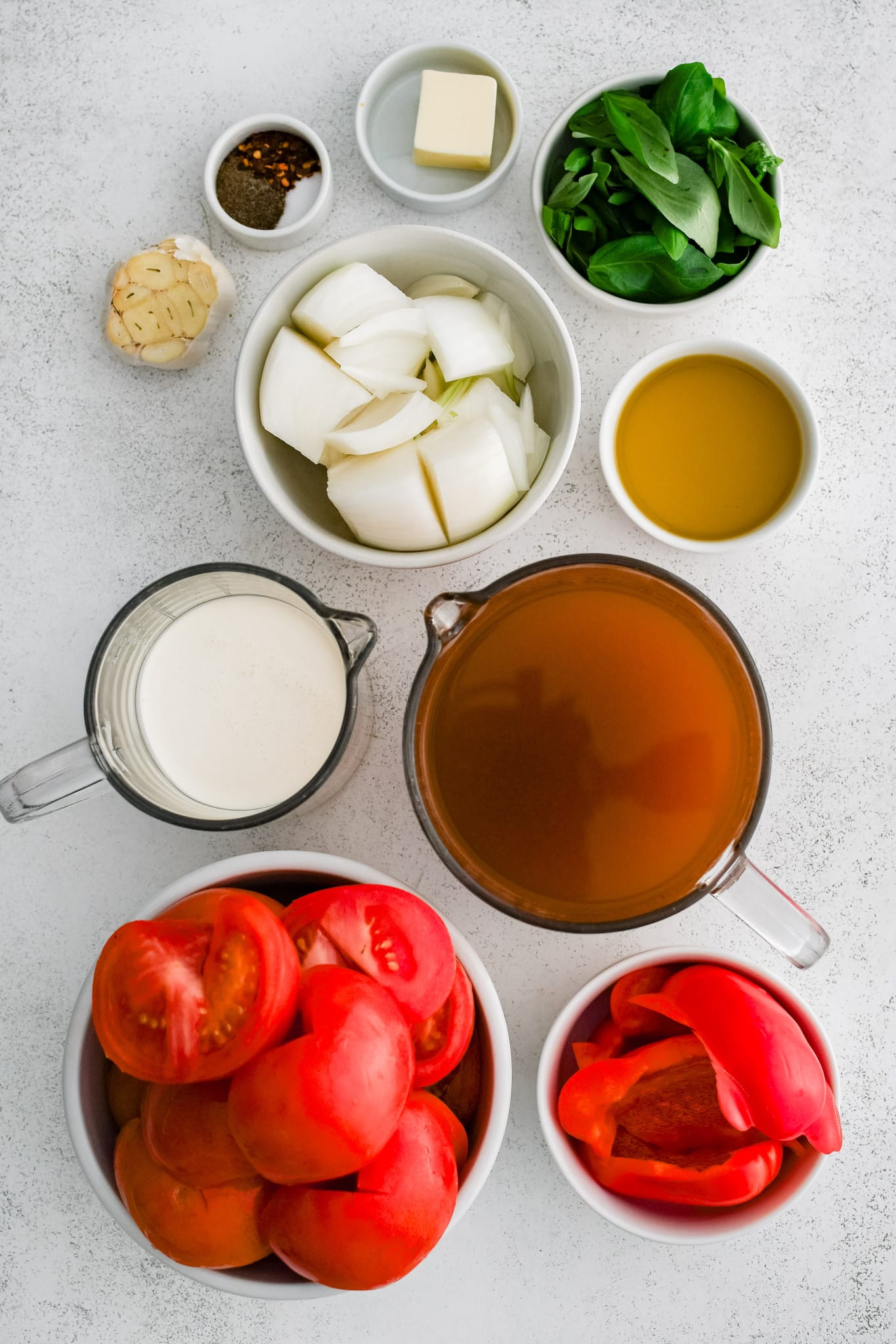 All of the ingredients needed to make tomato bisque in individual measuring cups and ramekins.