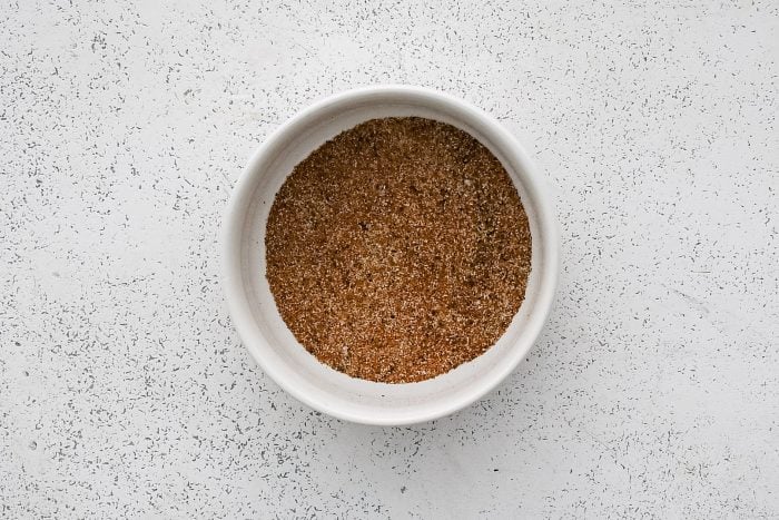 Seasoning combination of salt, black pepper, onion powder, garlic powder, and paprika in a small white ramekin.