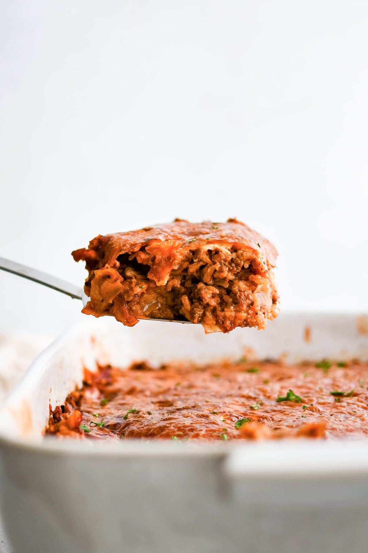 Metal spatula with a large serving of cabbage roll casserole made with green cabbage, rice, and ground beef in a comforting tomato sauce.