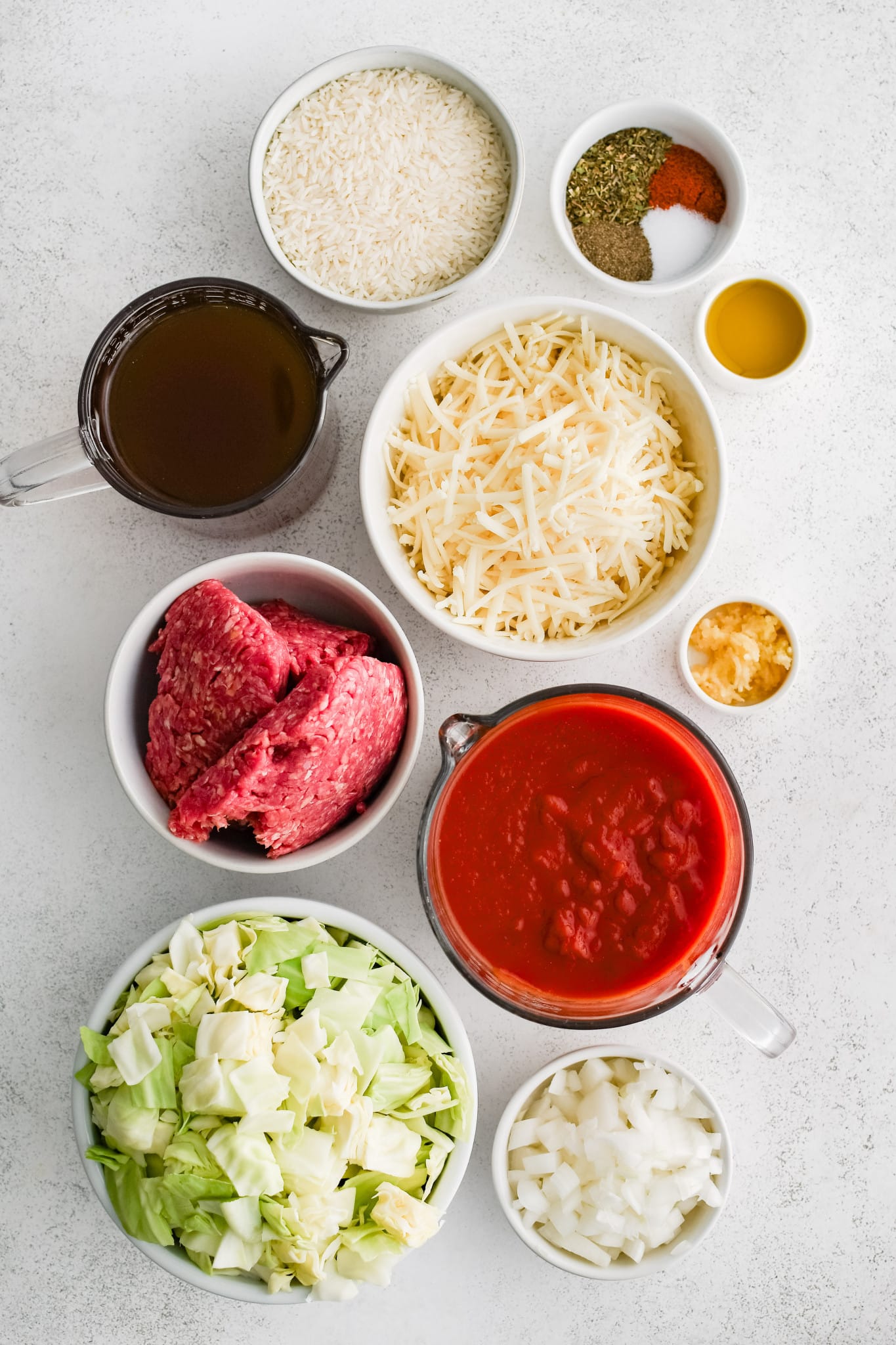 All of the ingredients needed to make cabbage roll casserole in individual bowls, measuring cups, and ramekins.