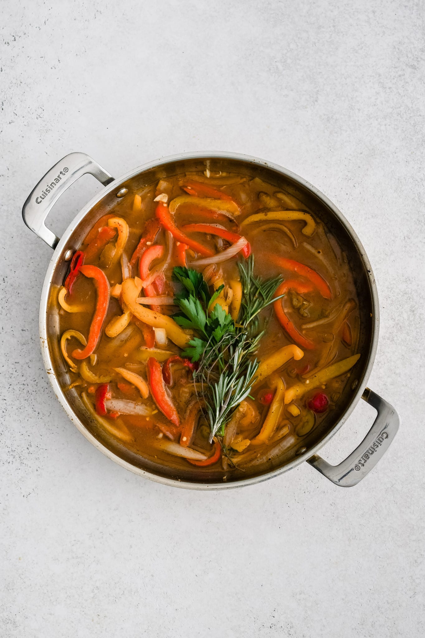 Softened bell peppers, onion, and garlic in a broth consisting of white wine, chicken broth, and cherry pepper juice, and topped with fresh sprigs of parsley, rosemary, and thyme.