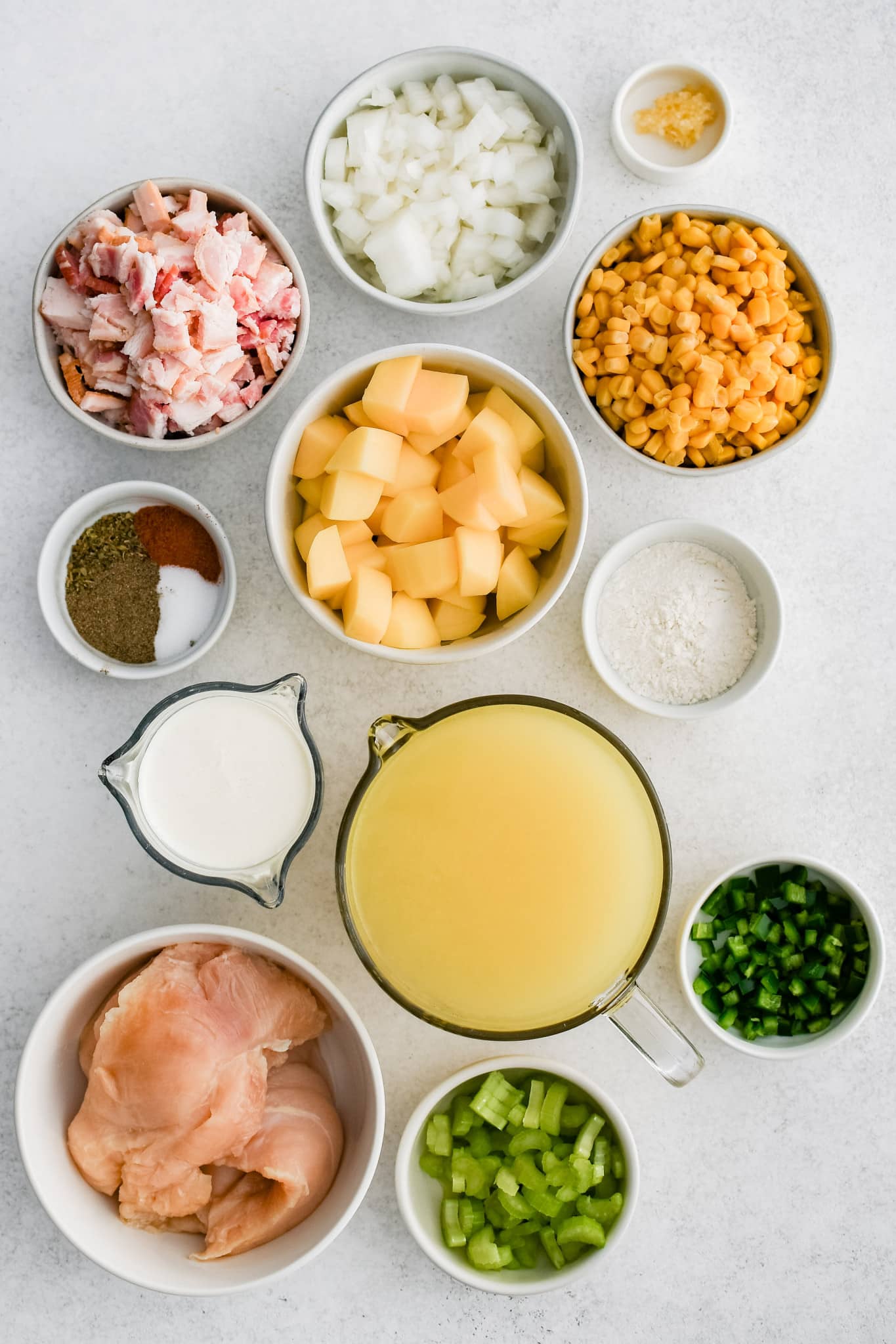 All of the ingredients needed to make chicken corn chowder in individual bowls, measuring cups, and ramekins.