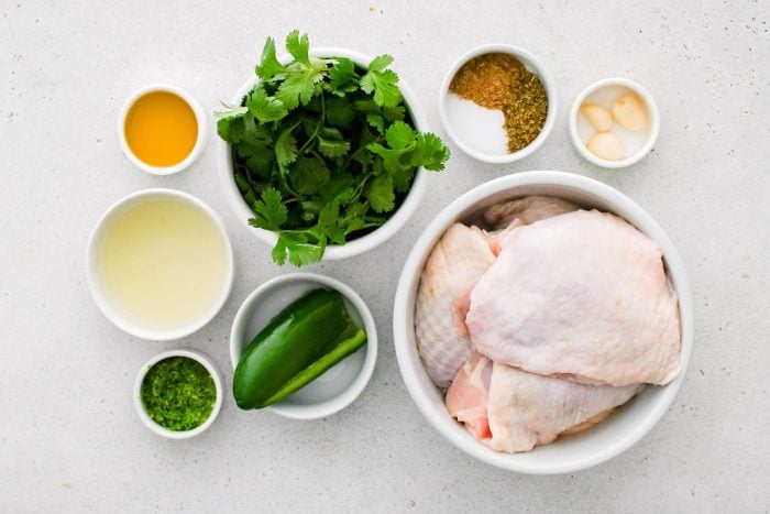 All of the ingredients needed to make cilantro lime chicken in individual bowls, measuring cups, and ramekins.