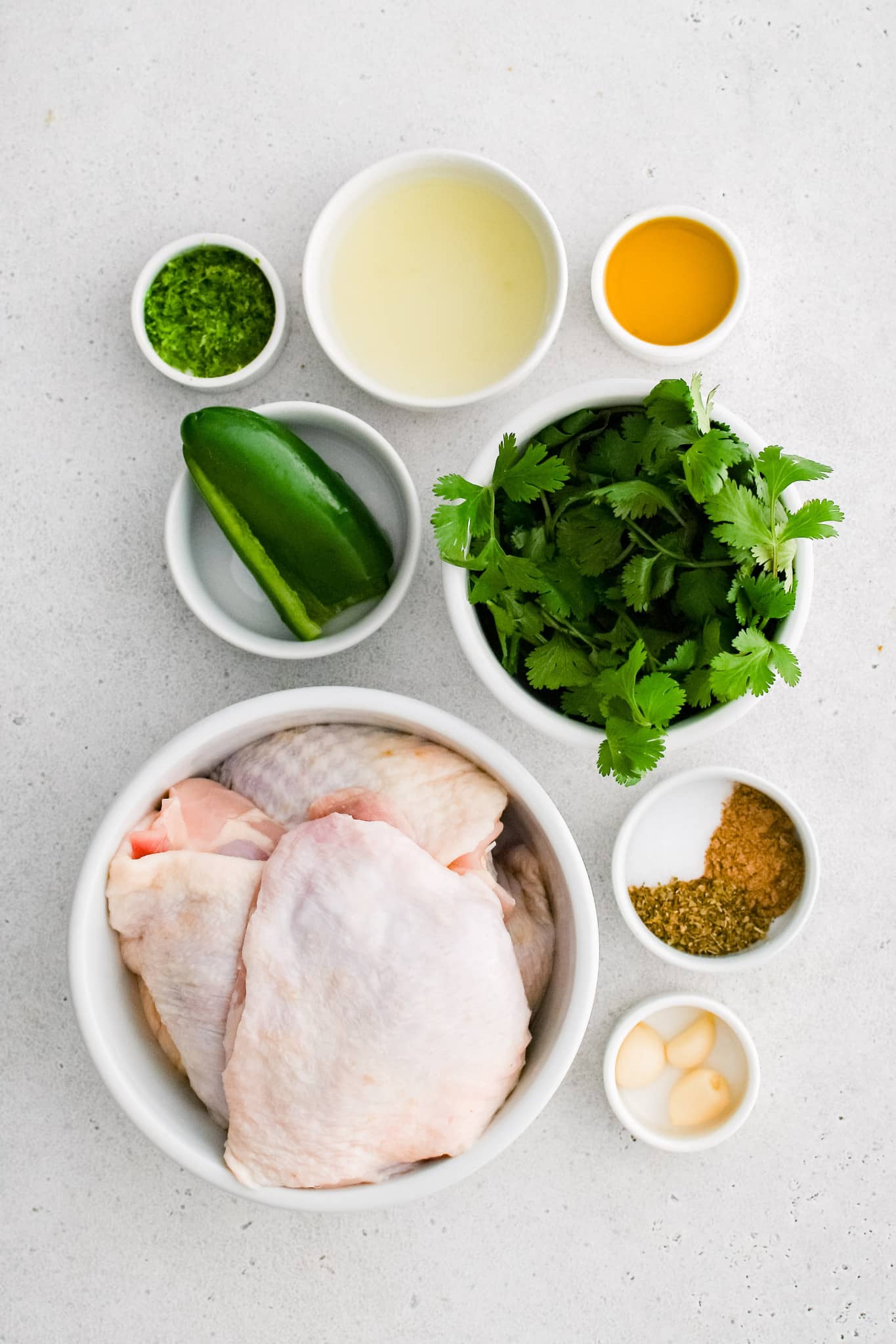 All of the ingredients needed to make cilantro lime chicken in individual bowls, measuring cups, and ramekins.
