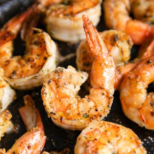 Cast iron skillet filled with juicy cooked tail-on shrimp marinated in cilantro lime marinade.