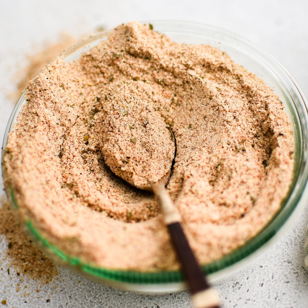 Glass jar filled with homemade Shake and Bake seasoning with a spoon set on top.