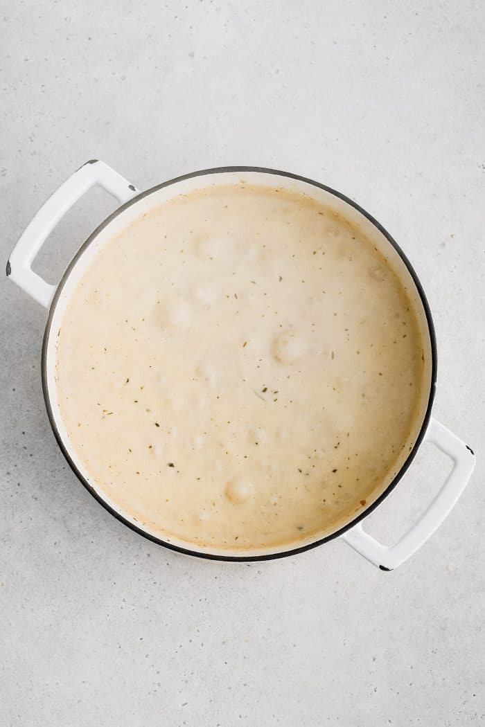 Simmering cream-based clam chowder filled with potatoes, clams, and diced vegetables.