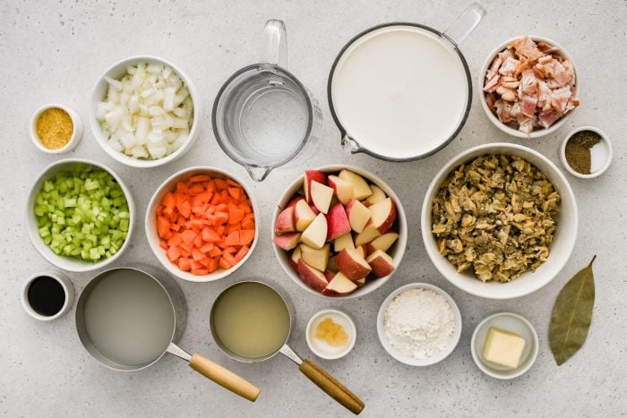 All of the ingredients needed to make New England clam chowder in individual bowls, measuring cups, and ramekins.