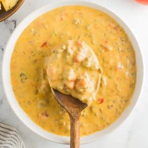 White bowl filled with gooey melted rotel cheese dip made with Velveeta cheese, ground beef, and canned Rotel.