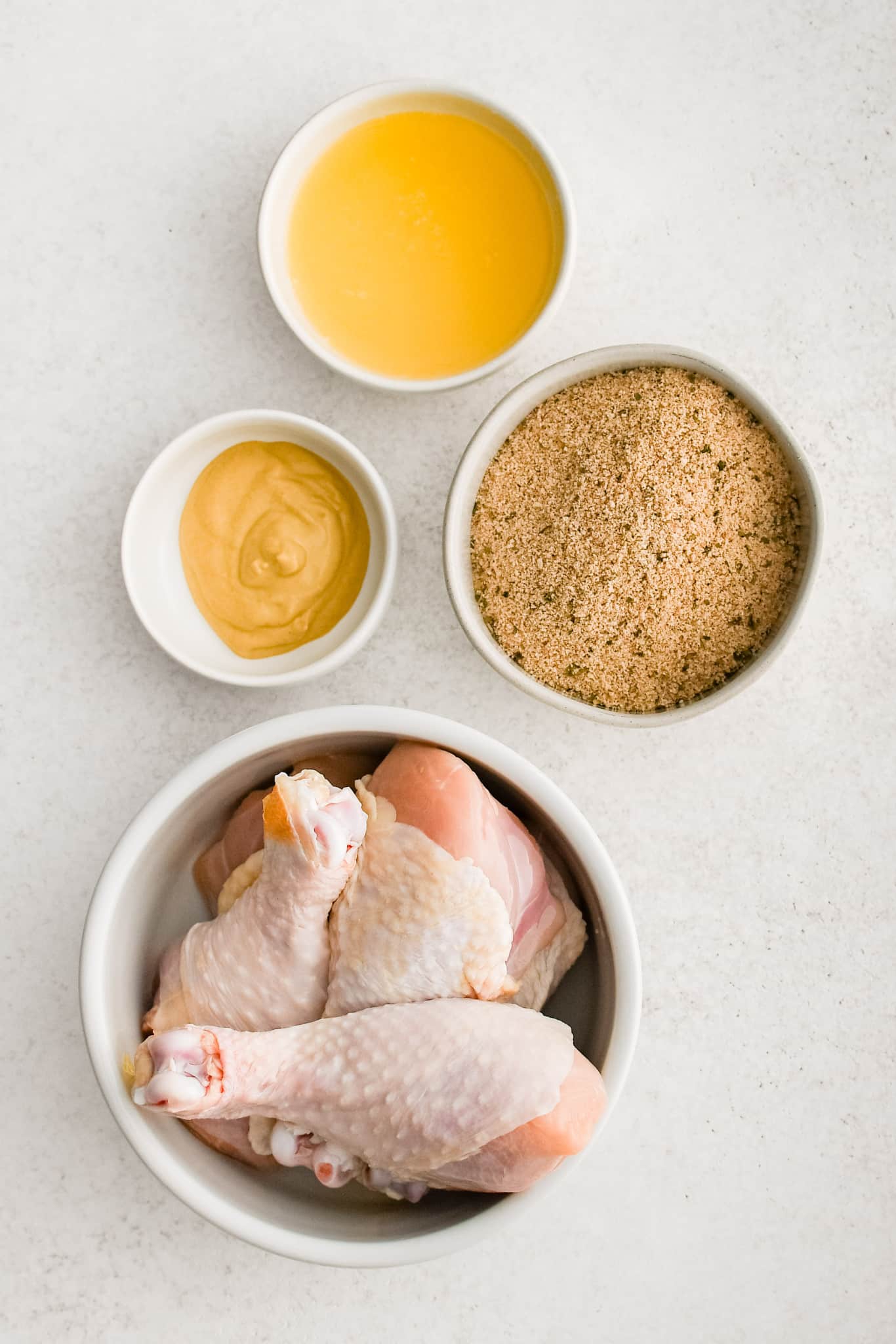 All of the ingredients needed to make homemade Shake and Bake chicken in individual bowls, measuring cups, and ramekins.