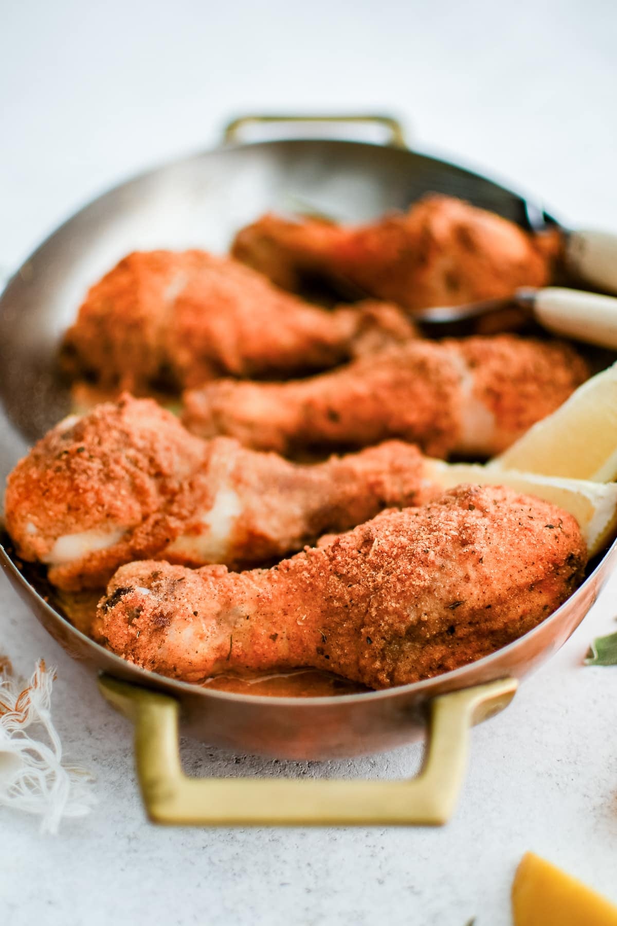 Oval-shaped baking dish filled with five golden, crispy baked chicken drumsticks coated in shake and bake seasoning.