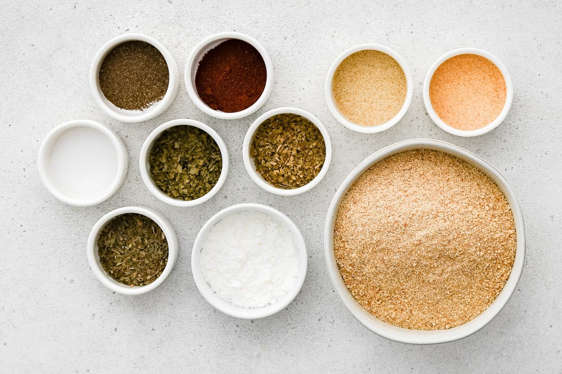 All of the ingredients needed to make homemade Shake and Bake in individual bowls, measuring cups, and ramekins.