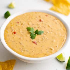 White bowl filled with melted Velveeta cheese dip with ground sausage and Rotel tomatoes.