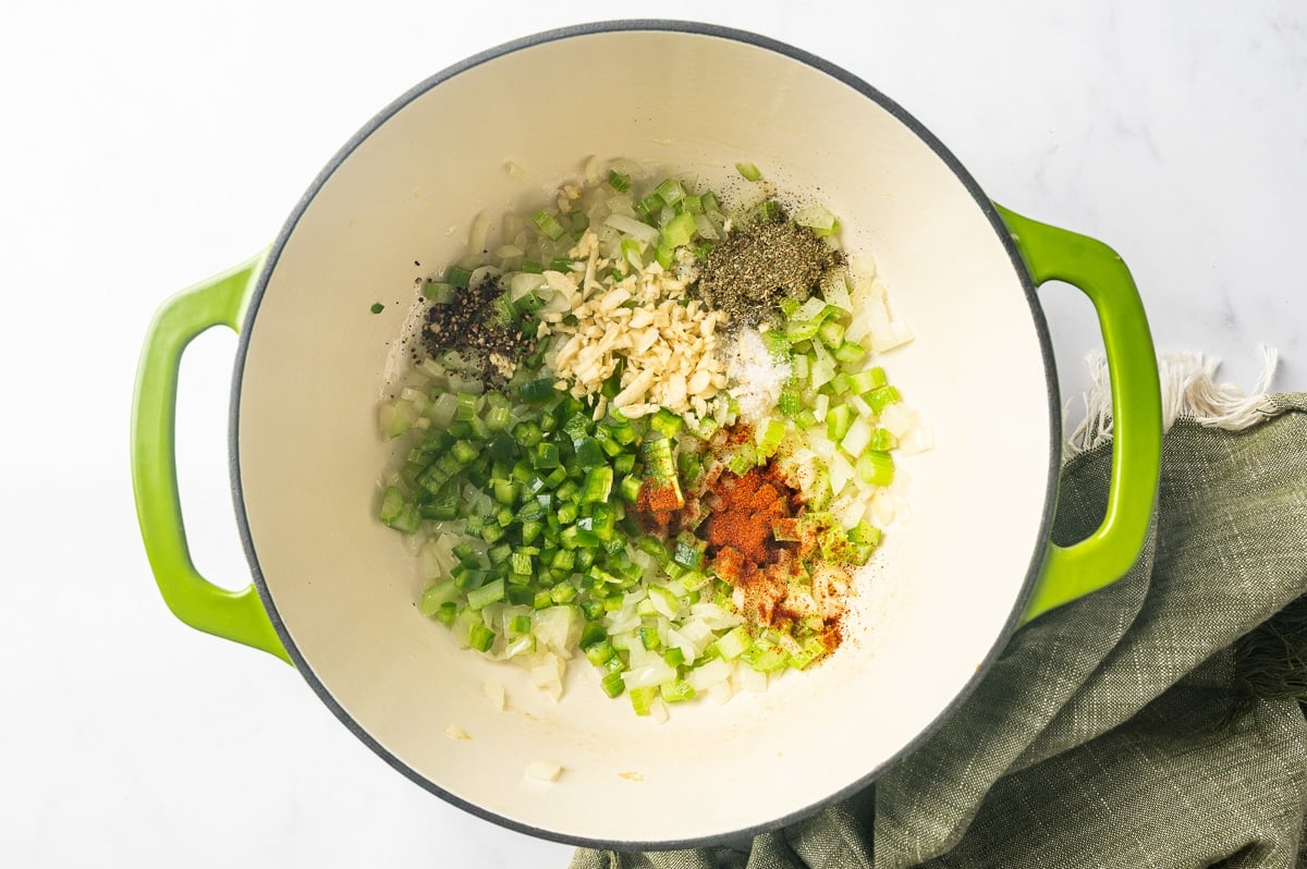 Softened onion and celery in a Dutch oven topped with chopped jalapeno, minced garlic, paprika, Italian seasoning, salt, and black pepper.