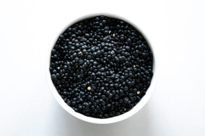 White bowl filled with dried black (Beluga) lentils.