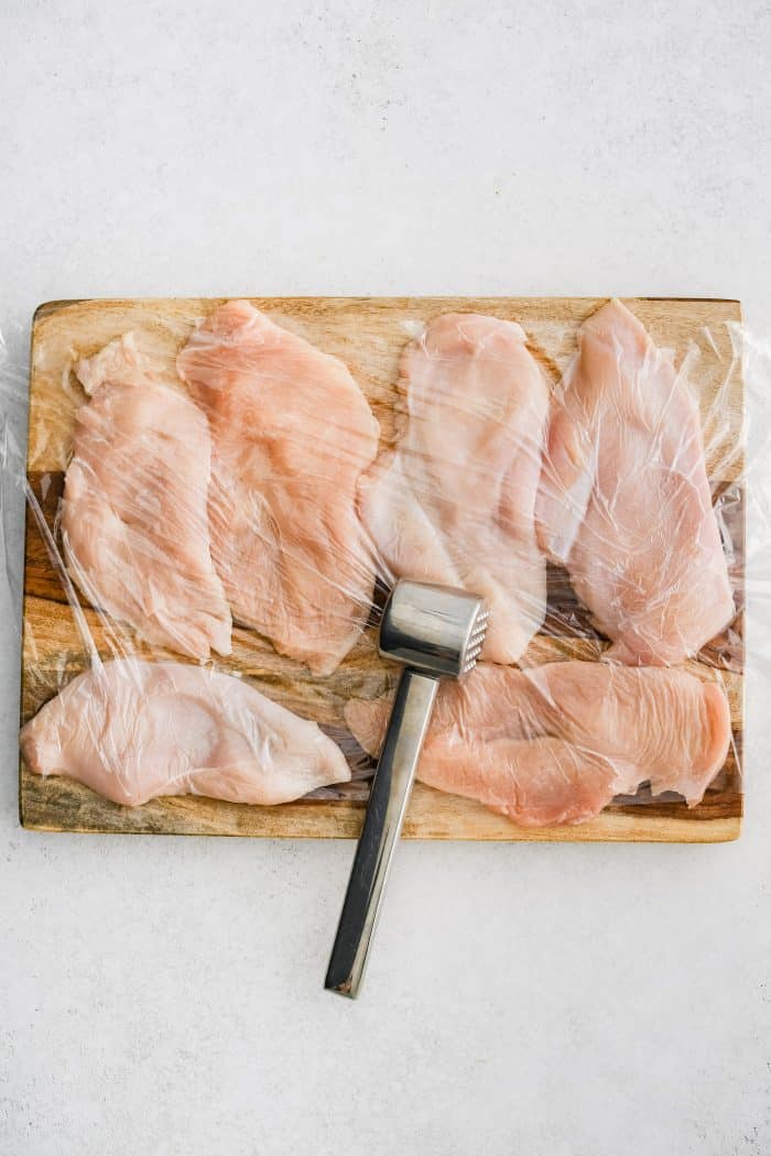 Pounding chicken cutlets to equal thickness with a meat mallet.