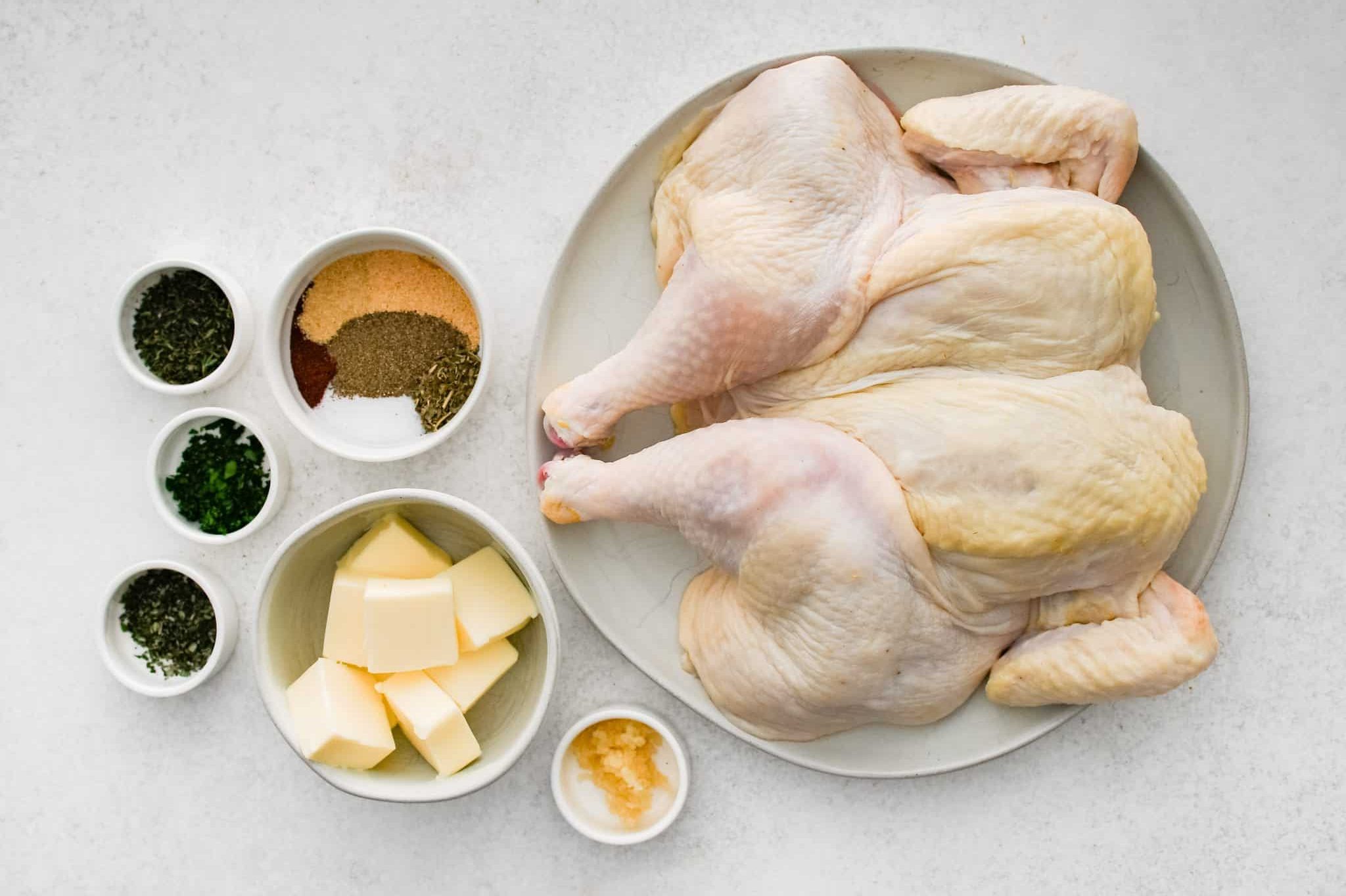 All of the ingredients needed to make Spatchcock Chicken Recipe in individual bowls, measuring cups, and ramekins.