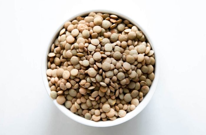 White bowl filled with dried green lentils.