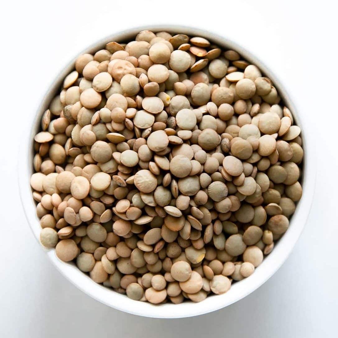 White bowl filled with dried green lentils.