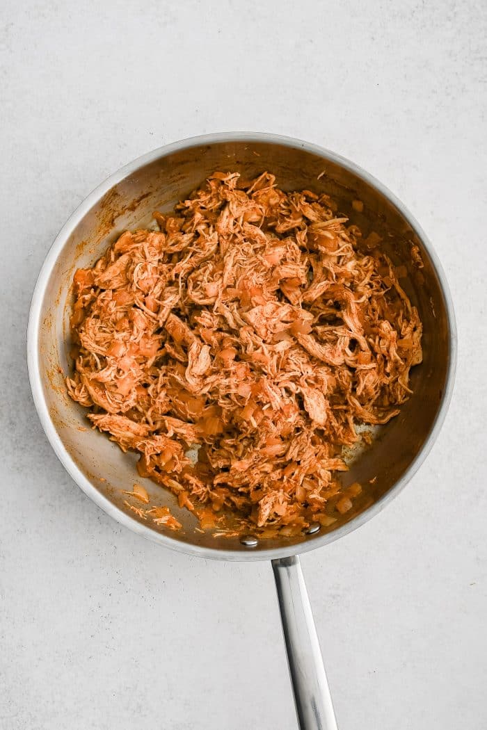 Seasoned shredded chicken in a large skillet.