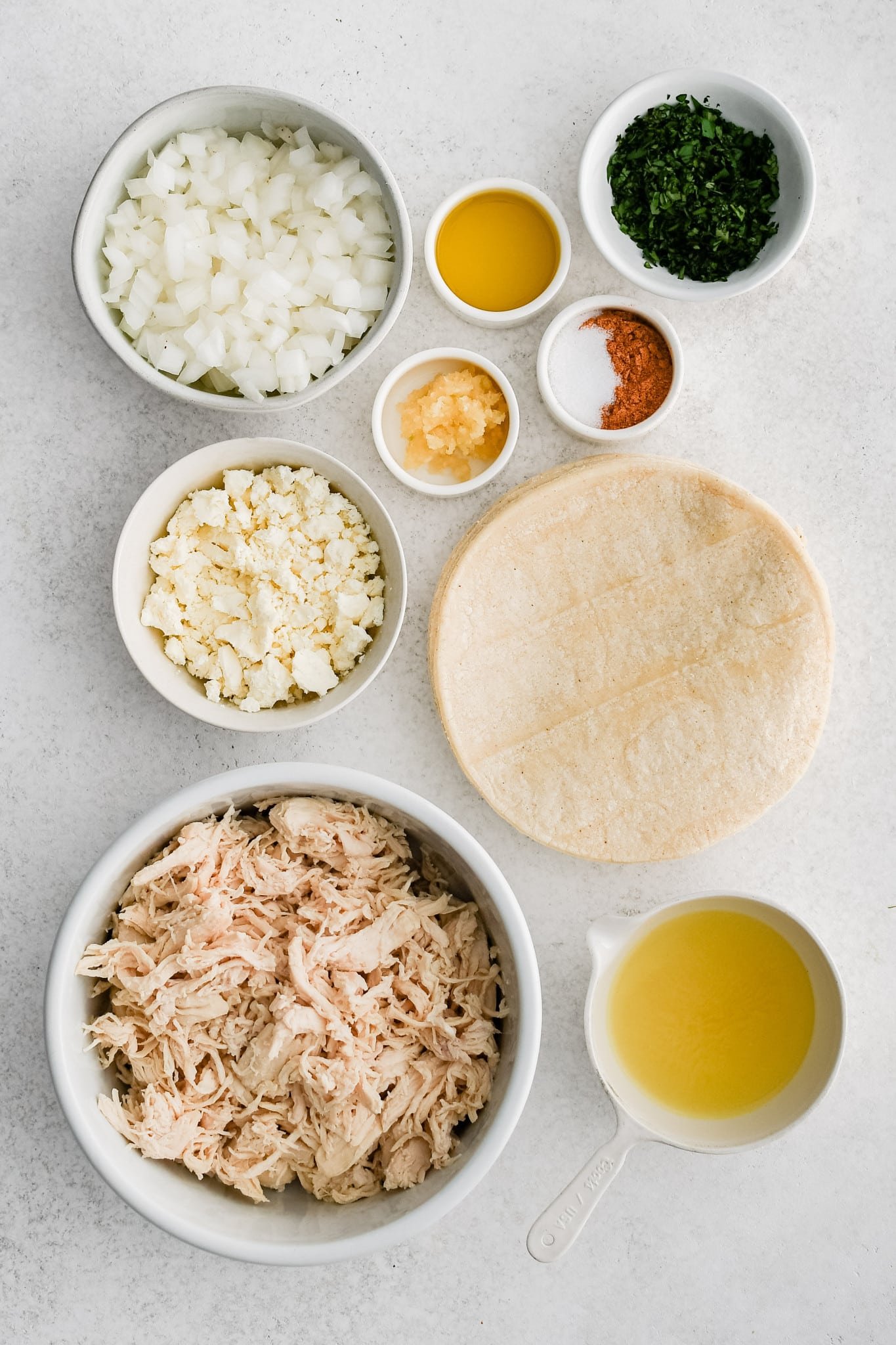 All of the ingredients needed to make Shredded Chicken Tacos in individual bowls, measuring cups, and ramekins.
