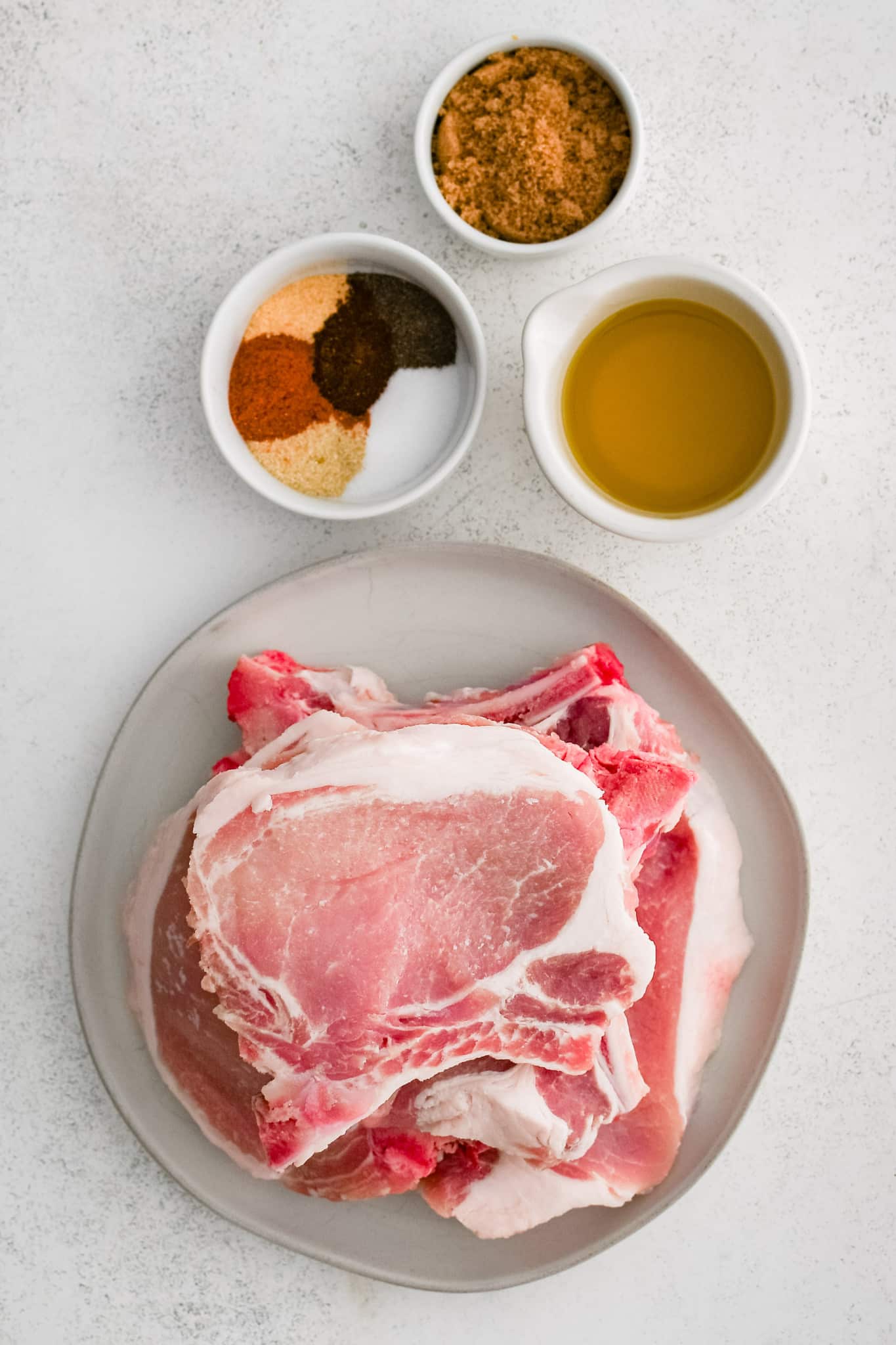 The ingredients for the bone-in pork chops recipe measured out and set aside in individual serving bowls.