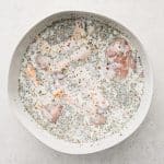 Chicken drumsticks submerged in buttermilk marinade
