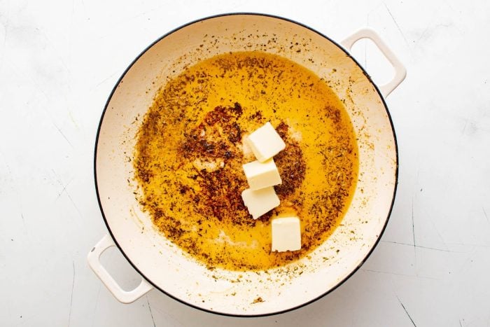 Butter is added to a large skillet used to cook chicken breasts.