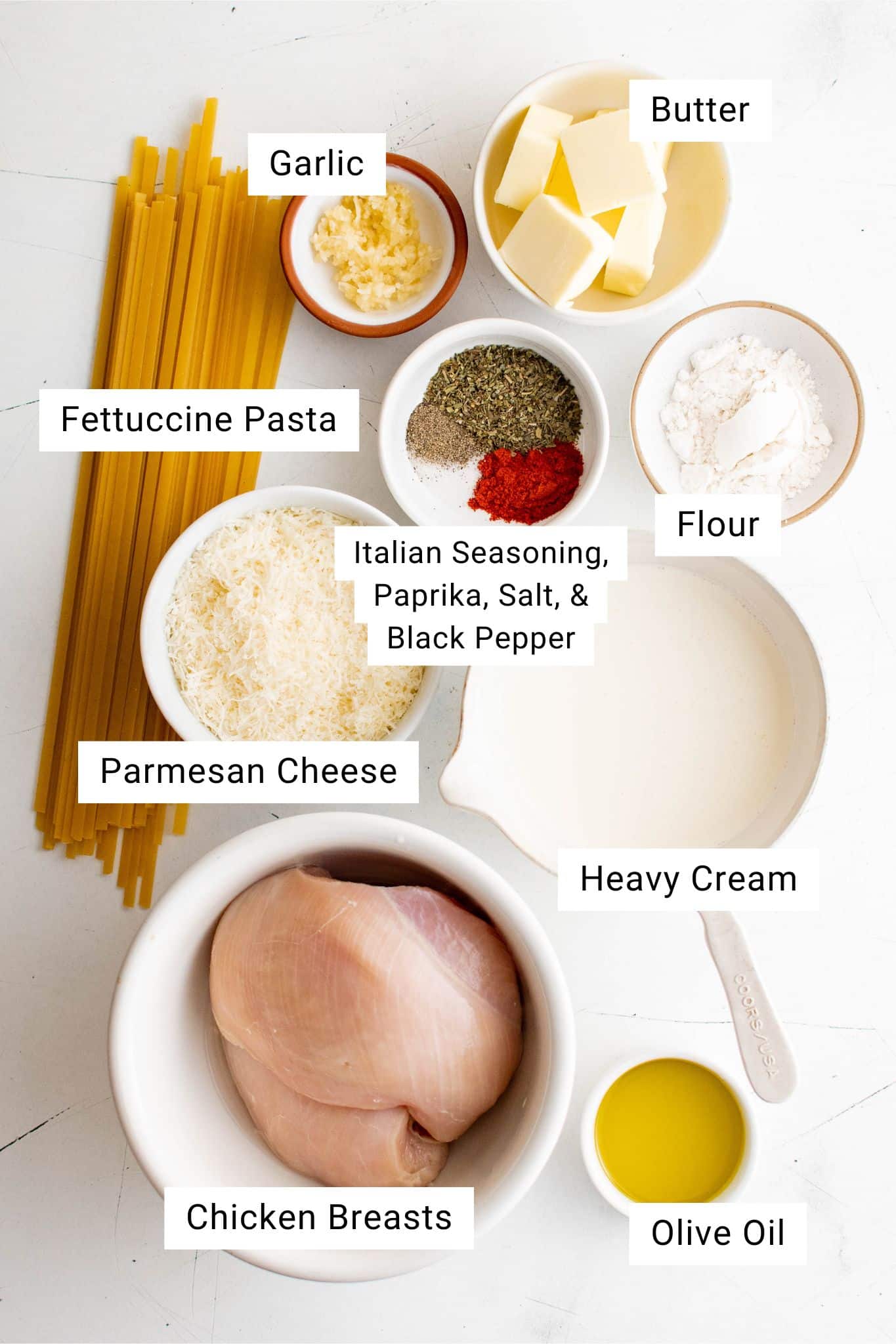 Ingredients for Chicken Alfredo Recipe measured and set aside in individual serving bowls with labeled text overlay.