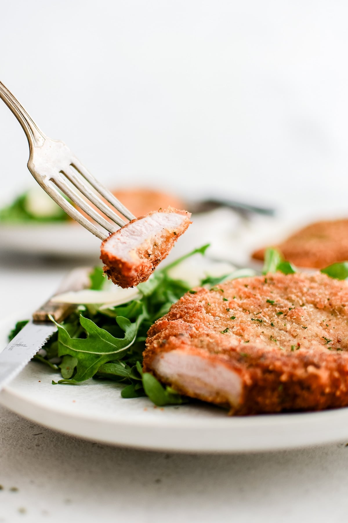 Corner cut from crispy pork Milanese displaying the juicy meaty inside and crispy breaded coating.