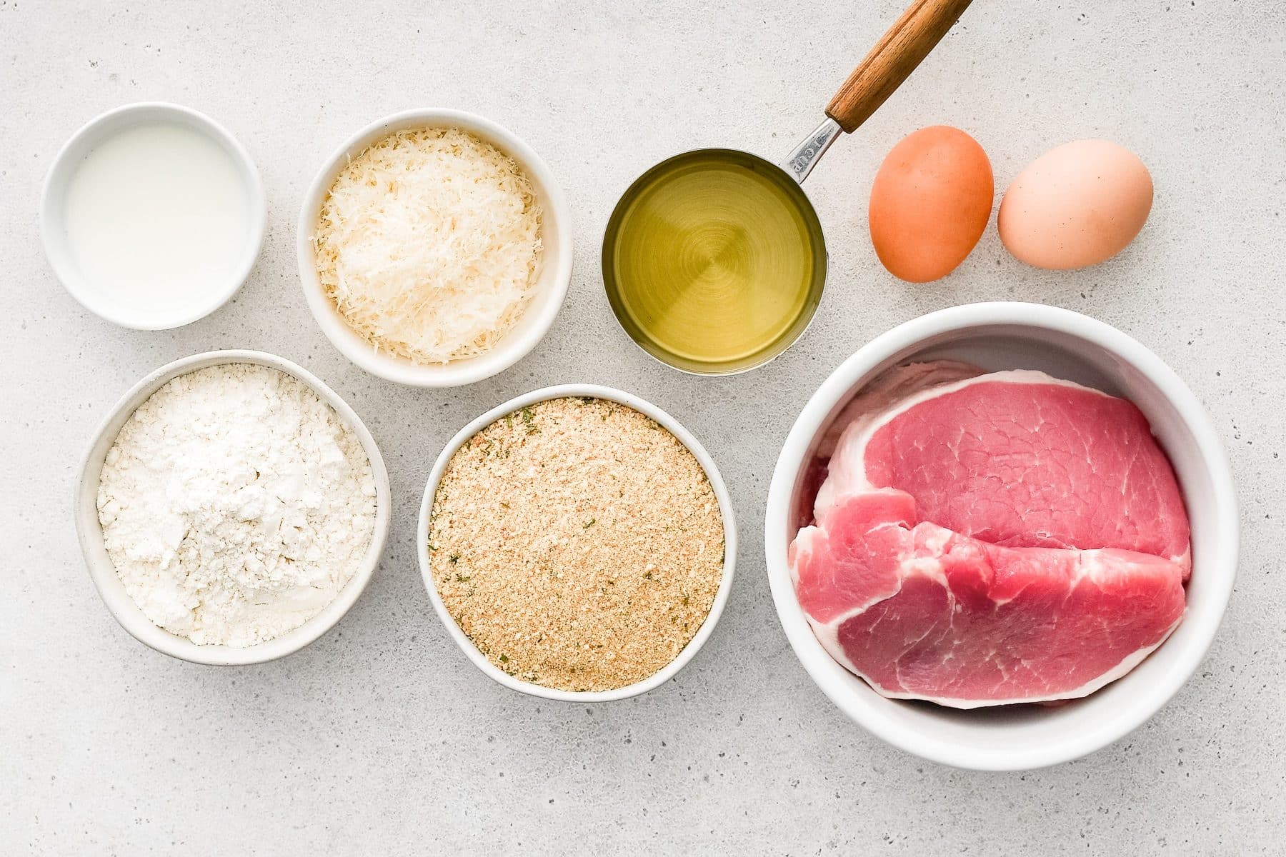 Ingredients for Pork Milanese Recipe measured out and set aside in individual serving bowls.