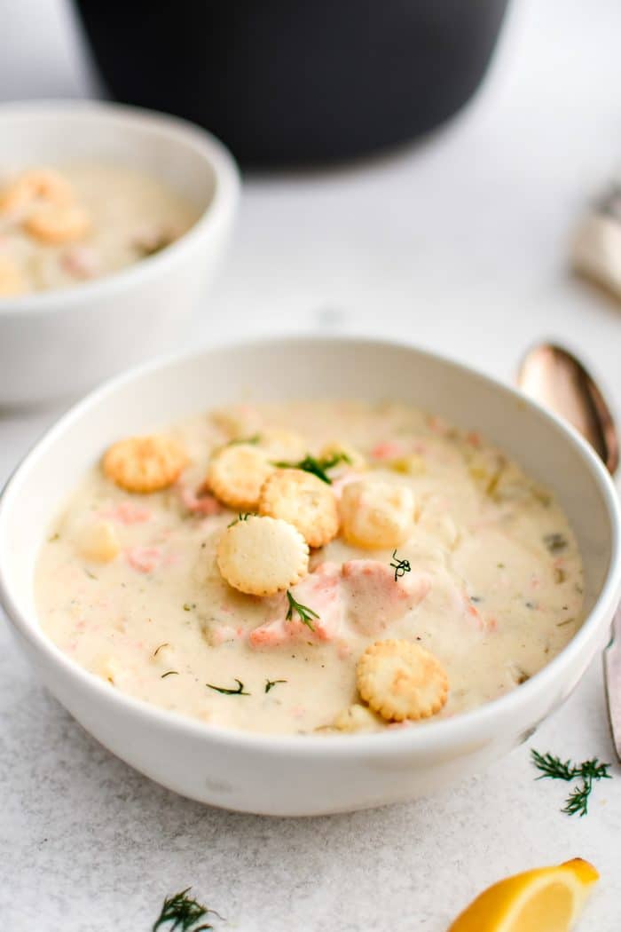 White bowl filled with thick and creamy salmon chowder with potatoes and fresh dill and garnished with Oyster crackers.