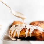 A close-up shot of Alabama White Sauce being drizzled over crispy golden-brown baked chicken legs.
