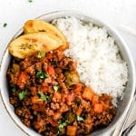 This is a Pinterest Pin for the best Cuban picadillo recipe, which uses ground beef, bell peppers, tomatoes, green olives, capers, potatoes, and raisins. It includes one image and a text overlay.