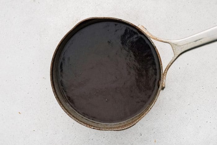 Slow cooker sauce reducing in a saucepan on the stovetop.