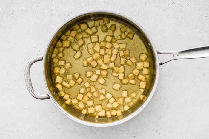Cubed potatoes frying in a skillet until golden brown.