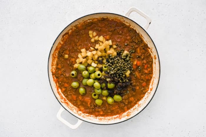 Green olives, raisins, and fried potatoes are added to the picadillo mixture.