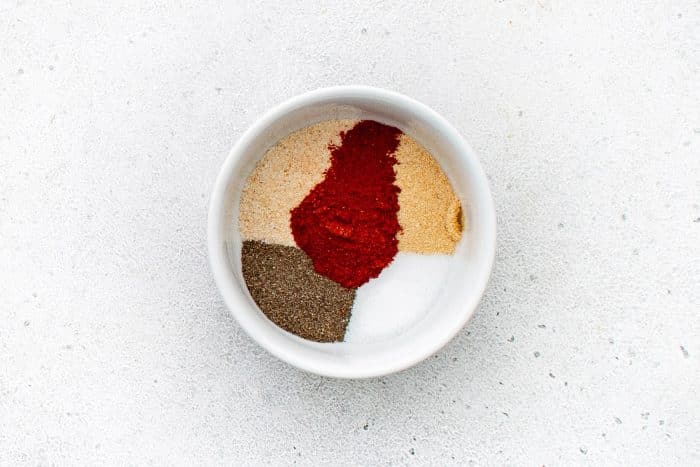 Small white bowl filled with salt, black pepper, smoked paprika, garlic powder, and onion powder.