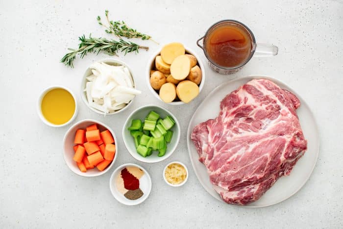 All ingredients for a One-Pot Dutch Oven Pork Roast recipe are presented in individual measuring cups and ramekins.