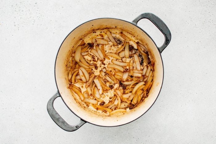 Thinly sliced onions and minced garlic cooking in the Dutch oven, turning translucent and fragrant.