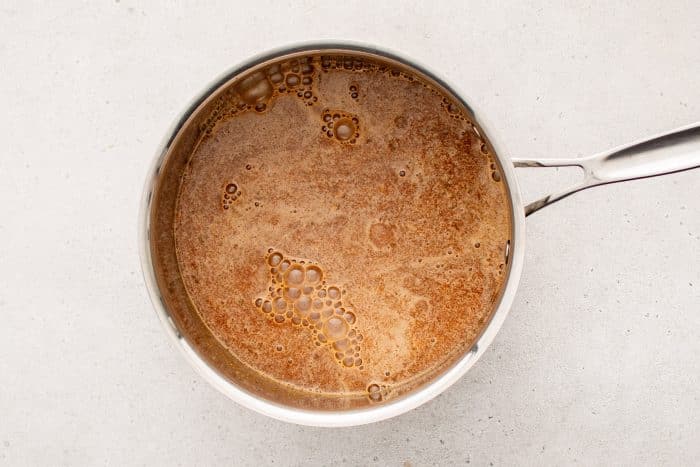 The blended sauce poured into a medium saucepan, simmering gently over low heat on a stovetop.