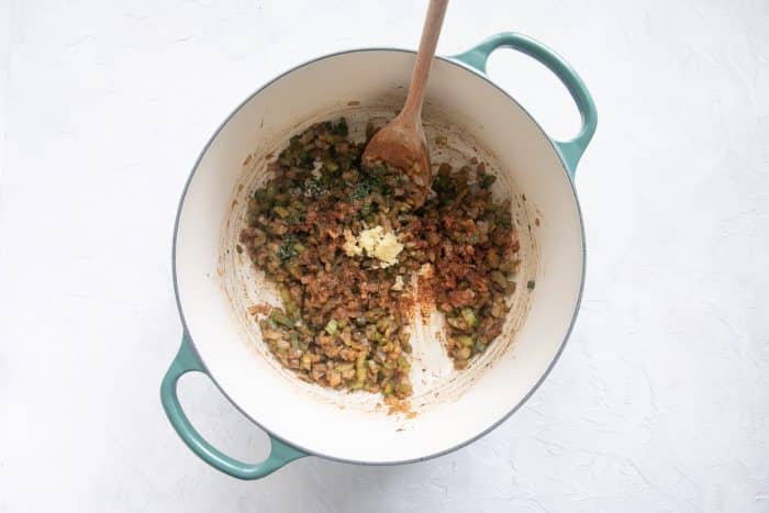 Minced garlic, fresh thyme, and a sprinkle of Cajun seasoning are added to the pot, mixing into the softened vegetables.